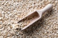 One wooden scoop on layer of rolled oats