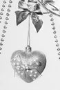 One Xmas toy silver sparkly heart with bow hanging on silver wood twigs close up.