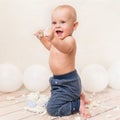 One year baby birthday party. Baby boy eating birthday cake. Cake smash with ballons on the background