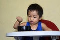 One 1 year old Asian baby boy learning to eat by himself, messy on baby dining chair at home Royalty Free Stock Photo