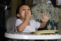 One 1 year old Asian baby boy learning to eat by himself by spoon, messy on baby dining chair at home Royalty Free Stock Photo