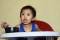 One 1 year old Asian baby boy learning to eat by himself by spoon, messy on baby dining chair Royalty Free Stock Photo