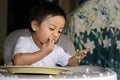 One 1 year old Asian baby boy learning to eat by himself by spoon, messy on baby dining chair Royalty Free Stock Photo