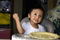 One 1 year old Asian baby boy learning to eat by himself by spoon, messy on baby dining chair Royalty Free Stock Photo