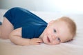 One year old baby boy in blue t-shirt lying in the bed on white bed sheet. Royalty Free Stock Photo