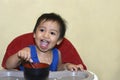 One 1 year old baby boy learning to eat alone smiling happy but messy Royalty Free Stock Photo