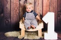 One year old baby boy sitting on chair in front of wooden background. One year concept with copy space Royalty Free Stock Photo