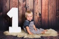 One year old baby boy sitting on chair in front of wooden background. One year concept with copy space Royalty Free Stock Photo