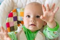 One year old baby looks and raises handles up. Little cheerful boy in a light green suit with sheep. Royalty Free Stock Photo