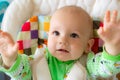 One year old baby looks and raises handles up. Little cheerful boy in a light green suit with sheep. Royalty Free Stock Photo