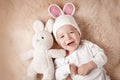 One year old baby lying in bunny hat on lamb wool