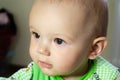 One year old baby is sitting and attentively looking somewhere. Little cheerful boy in a light green suit with sheep. Royalty Free Stock Photo