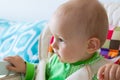 One year old baby is sitting and attentively looking somewhere. Little cheerful boy in a light green suit with sheep. Royalty Free Stock Photo