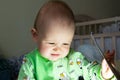 One year old baby is sitting and attentively looking somewhere. Little cheerful boy in a light green suit with sheep. Royalty Free Stock Photo