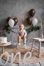 One year old birthday, rustic minimalist decorations and a little boy, balloons and a wooden background, birthday cake Royalty Free Stock Photo