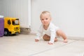 One year old blond baby boy sitting on floor at home and looking at camera. Little kid is crawling on all four Royalty Free Stock Photo