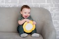 The one-year-old boy is sitting on a gray sofa with a book Royalty Free Stock Photo