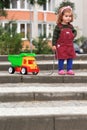 One year old curly girl pulling a truck trying to surmount an obstacle of steps