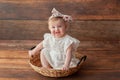 One year old girl. With headband. Girl sitting in a wicker basket. Royalty Free Stock Photo