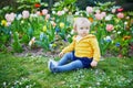 One year old girl sitting on the grass with colorful tulips Royalty Free Stock Photo