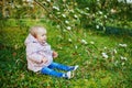 One year old girl sitting on the grass under tree branch in bloom Royalty Free Stock Photo