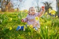 One year old girl sitting on the grass with yellow narcissi Royalty Free Stock Photo