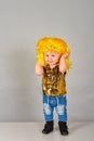 One year old girl in a yellow wig. A small child in jeans and sequins poses in a modeling agency