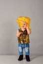 One year old girl in a yellow wig. A small child in jeans and sequins poses in a modeling agency