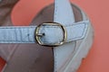 One yellow closed metal clasp on a white leather sandal harness