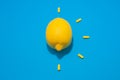 One yellow lemon and five pills on blue background