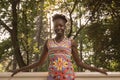 one, young adult, black african american happy smiling woman 20-29 years, standing, leaning on fence, looking to camera, outdoors Royalty Free Stock Photo