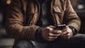 One young adult male sitting outdoors holding smart phone texting generated by AI Royalty Free Stock Photo