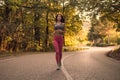 one young adult woman, running jogging, forest woods, asphalt road lane, sunset sunrise daylight, sport clothes Royalty Free Stock Photo