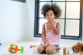 One young African girl sit and express of frighten or shock during plays some toys in the living room