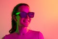 One young caucasian girl in sunglases smiling isolated over gradient studio background in neon lights. Cropped image Royalty Free Stock Photo