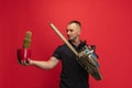 One young caucasian man with cactus and electric saw posing over red background.