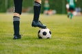 One young football player with ball on grass field. Boy in a sportswear.