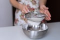 One young girl sifts flour into a bowl.