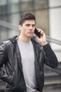 One young handsome man posing outdoors, wearing jacket, talking over smartphone Royalty Free Stock Photo