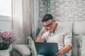 One young happy man surfing the net using his laptop at home sitting on the sofa enjoying free time and relaxing alone. Royalty Free Stock Photo