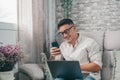 One young happy man surfing the net using his laptop at home sitting on the sofa enjoying free time and relaxing alone. Royalty Free Stock Photo