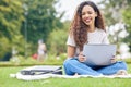 One young hispanic woman working on her laptop while sitting outside on an open field. A beautiful mixed race female Royalty Free Stock Photo