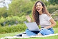 One young hispanic woman working on her laptop while sitting outside on an open field. A beautiful mixed race female Royalty Free Stock Photo