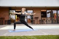 One young lady,20-29 years, old doing yoga on a yoga matt in a backyard of a beautiful fancy house