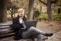 One young laughing man, sitting on bench in public park, using laptop, talking over Internet, video chat or call, could be with Royalty Free Stock Photo