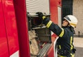 One young male firefighter dressed in uniform with protective helmet near fire engine.