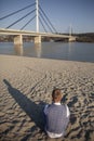 One young man, formal wear, sitting on beach alone