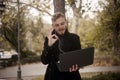 One young man, holding laptop in one hand outside in park, communicating over Internet, video chat or call, could be with family,