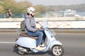 One young man riding a light blue vintage vespa scooter on the city street bridge