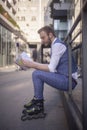 One young man siting while wearing inline skates and holding a notebook